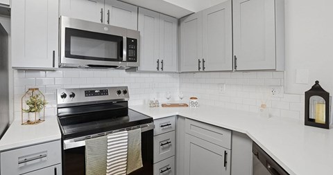 A modern kitchen with a black stove top oven and white cabinets.