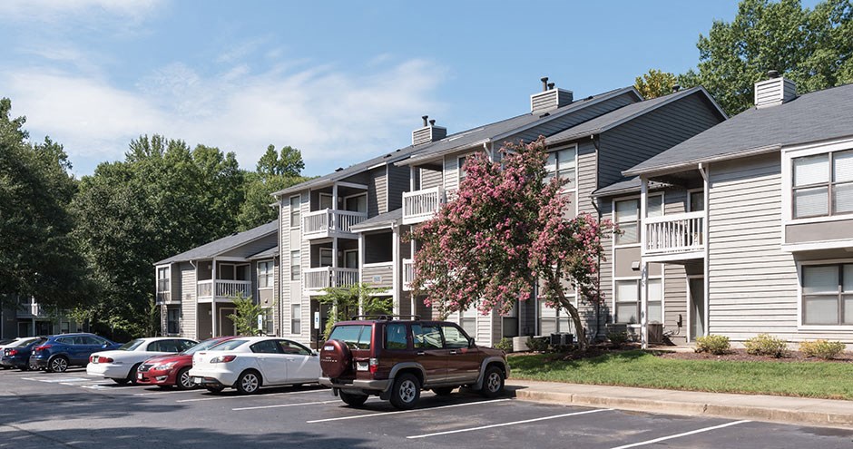 an apartment building with cars parked in a parking lot