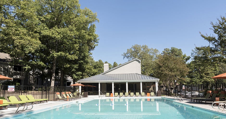 a swimming pool with a pavilion and chairs around it
