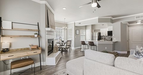 A modern living room with a grey couch and a kitchen area in the background.