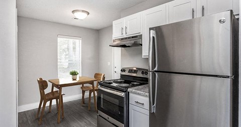 A kitchen with a stainless steel refrigerator, oven, and dining table with chairs.