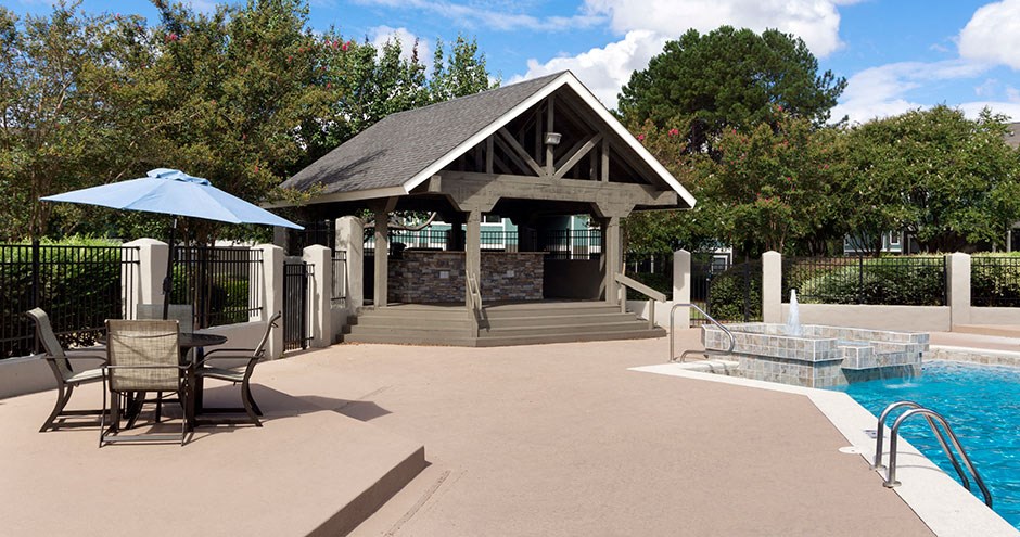 a gazebo next to a pool with chairs and a table