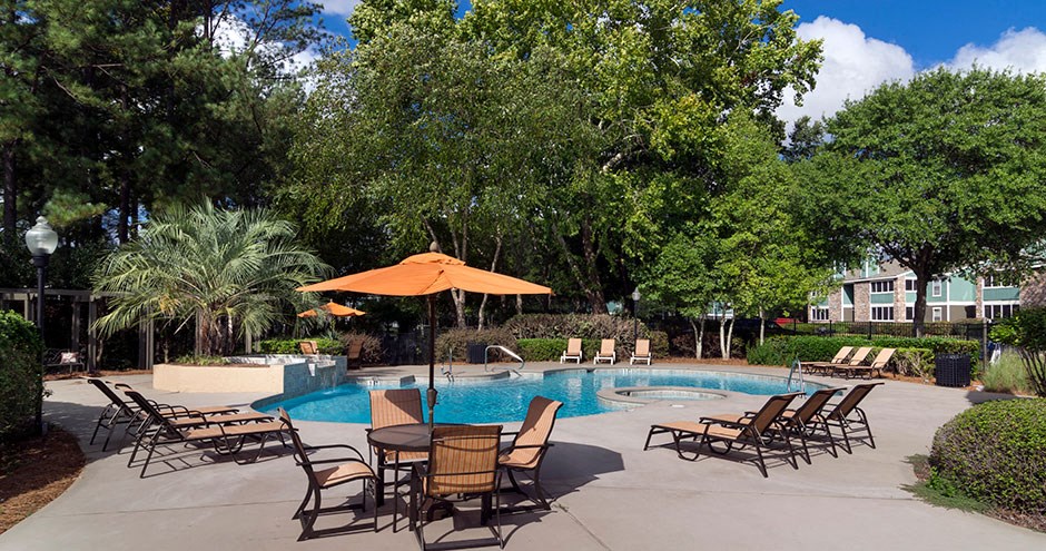 a swimming pool with patio furniture and umbrellas