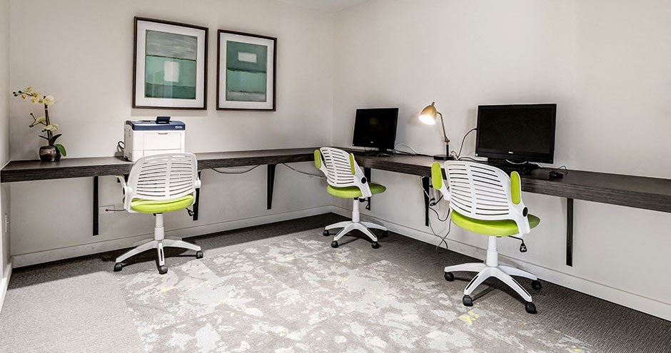 two computer desks in a room with chairs and monitors