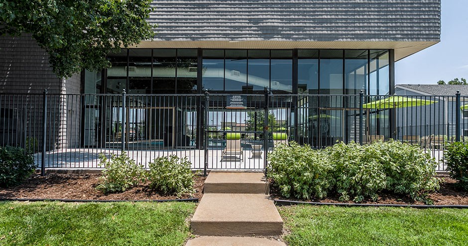 the front of a building with a walkway and plants