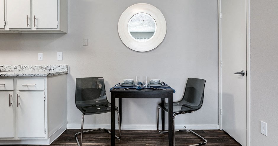 a small table with two chairs in a kitchen under a round window