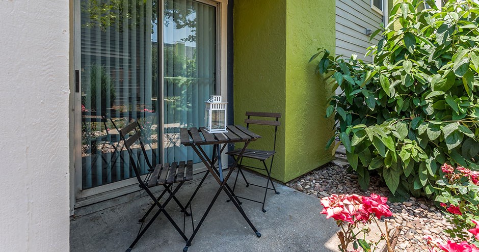 a patio with two chairs and a table and a window