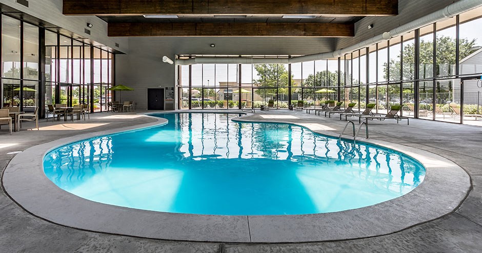 a large swimming pool in a building with glass doors and windows