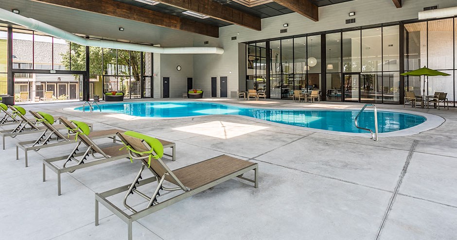 a swimming pool and lounge chairs in front of a building