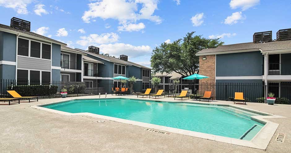 a swimming pool with yellow chairs and umbrellas in front of a building