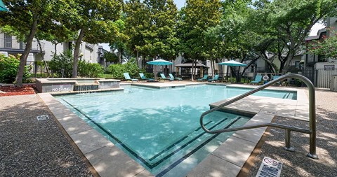 A pool surrounded by trees and a metal railing.