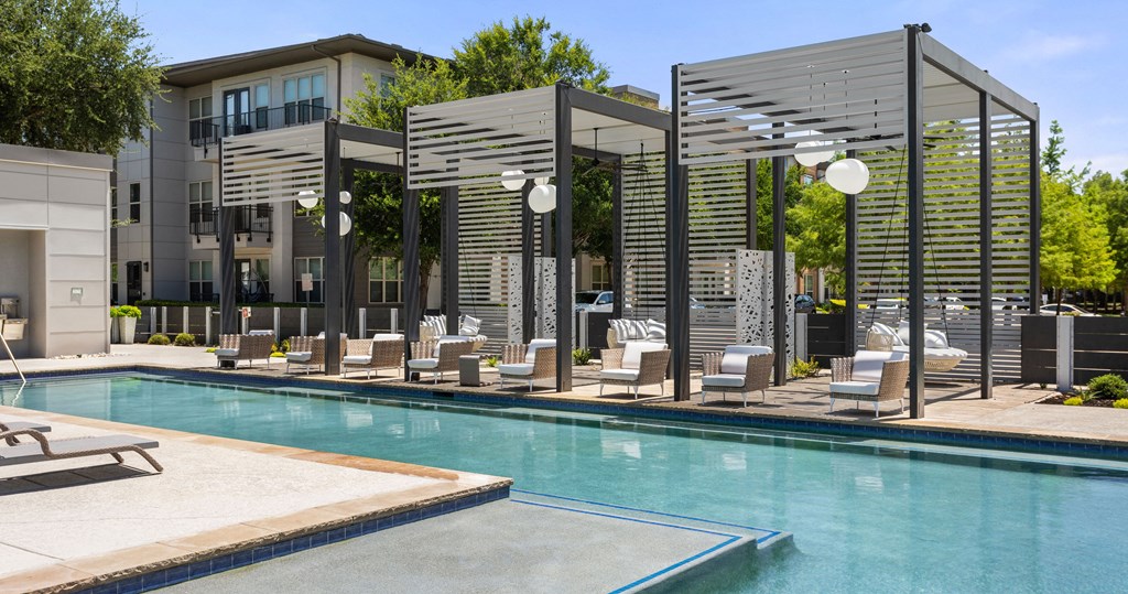 a swimming pool with lounge chairs and a building in the background