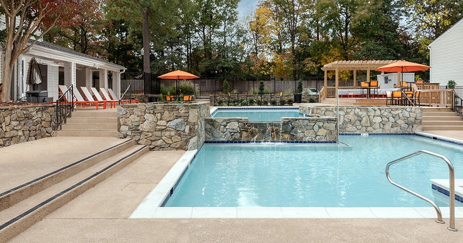 a pool and spa in a backyard next to a house