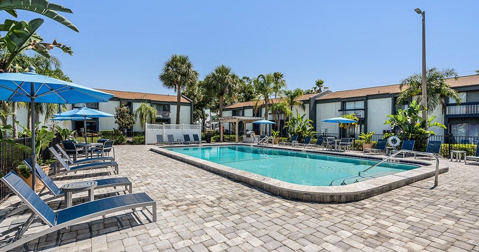 a swimming pool with lounge chairs and umbrellas in front of a building