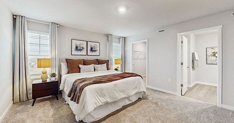 A bedroom with a large bed and a window with curtains.