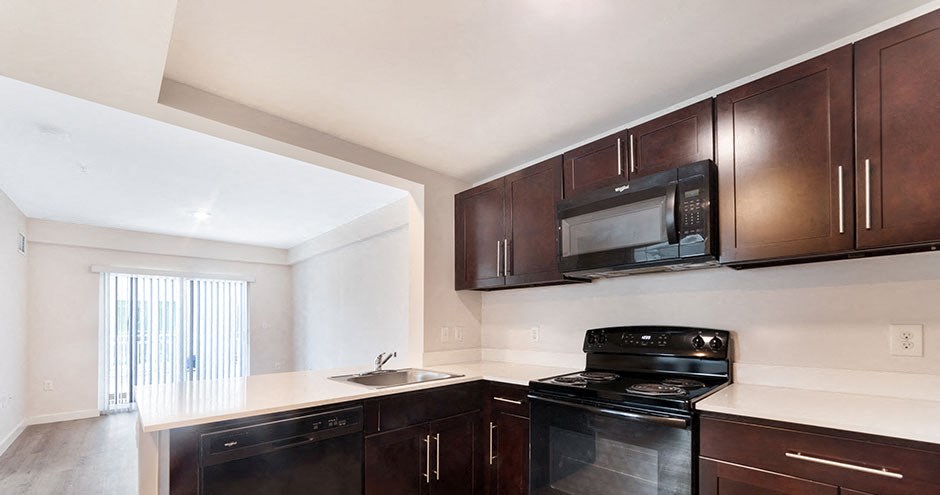 an empty kitchen with black appliances and wooden cabinets