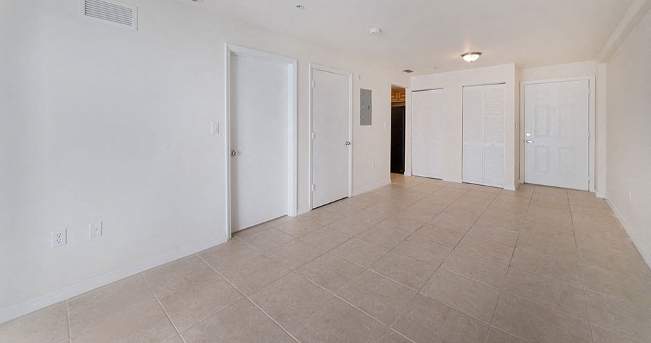 an empty living room with white doors and a tile floor