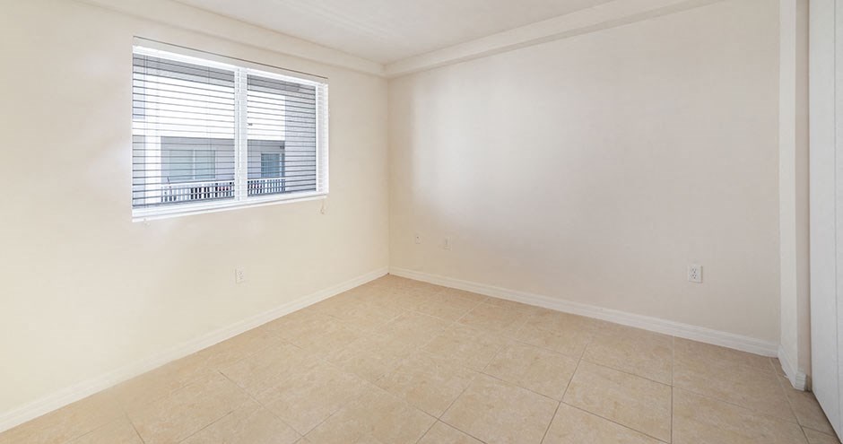 an empty living room with a window and a tiled floor