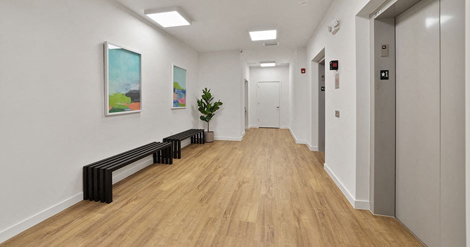 a long hallway with white walls and wood flooring and a painting on the wall