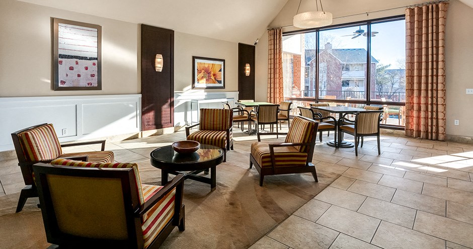 a living room with chairs and tables and a large window