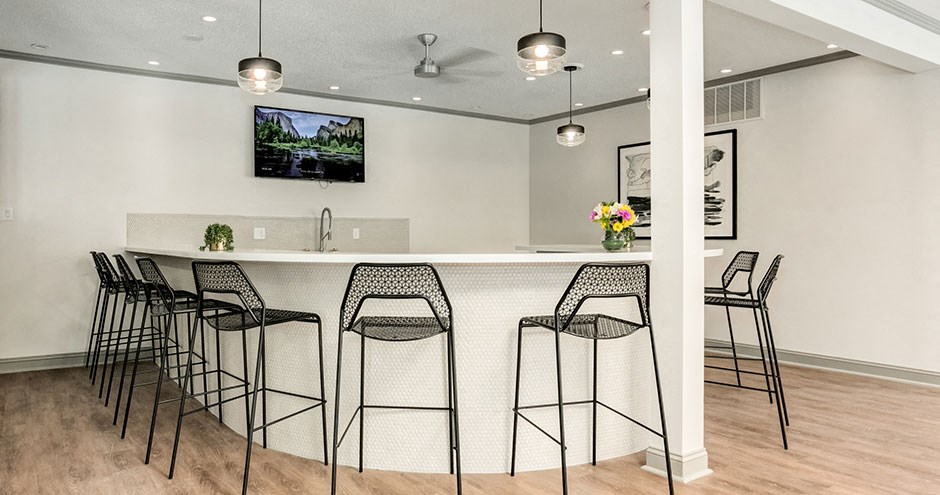 a bar with bar stools in a living room with a television