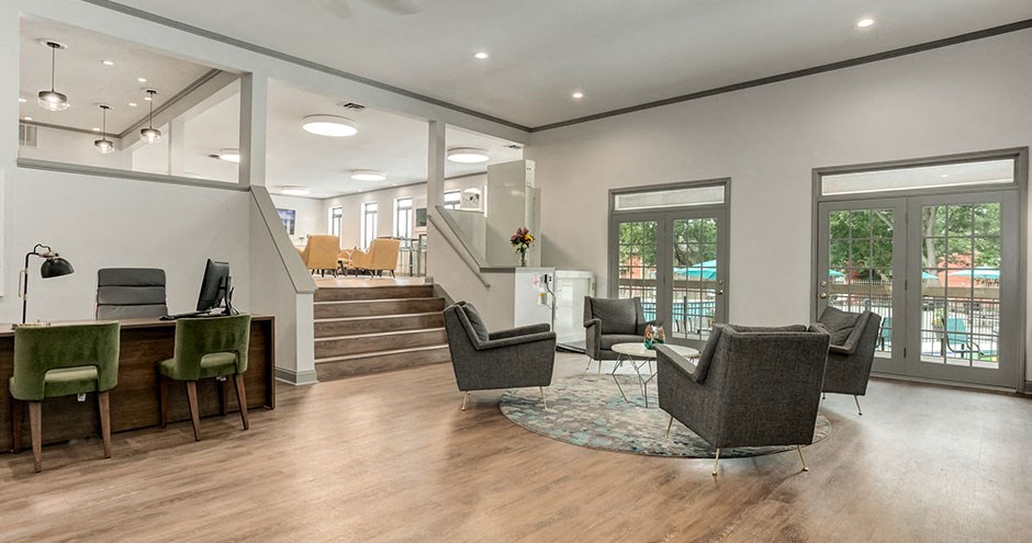 a living room with a desk and chairs and a staircase