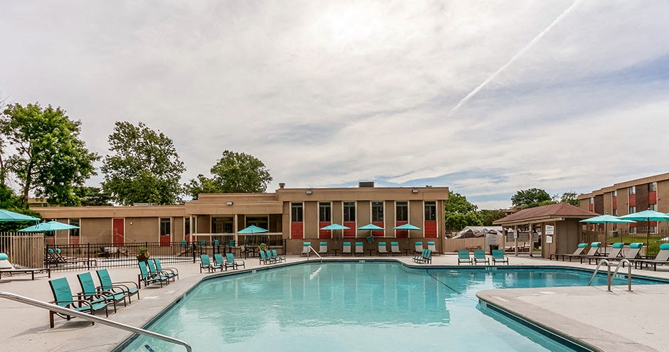 a swimming pool with chairs and umbrellas in front of a building