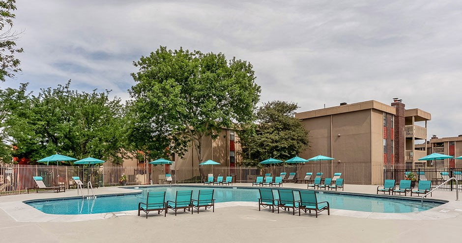 a swimming pool with chairs and umbrellas in front of a building
