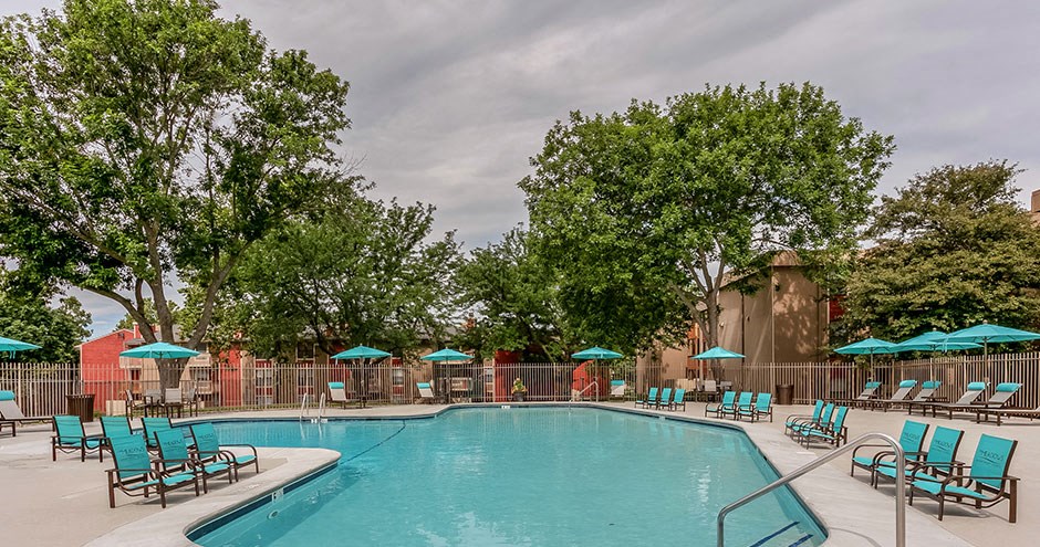 a swimming pool with blue chairs and umbrellas