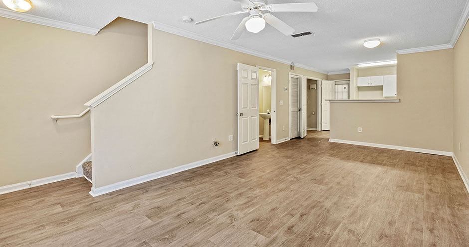 an empty living room with a ceiling fan