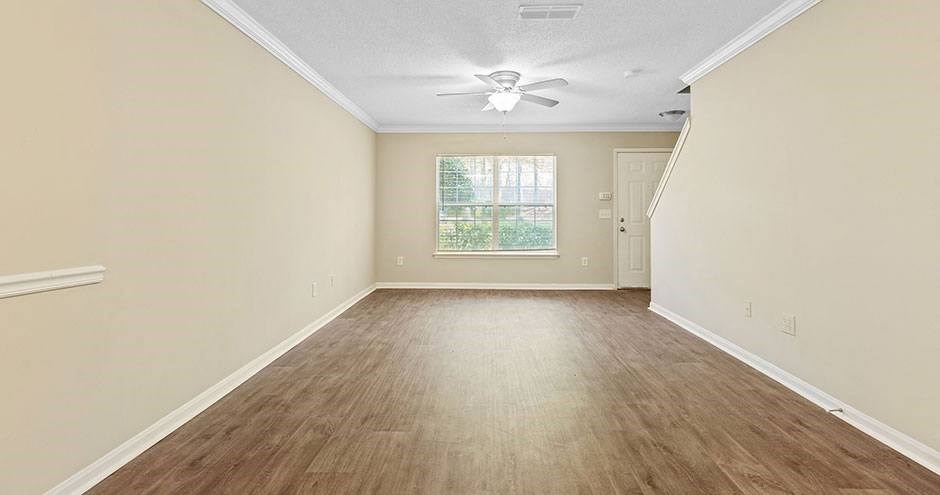 an empty living room with a ceiling fan