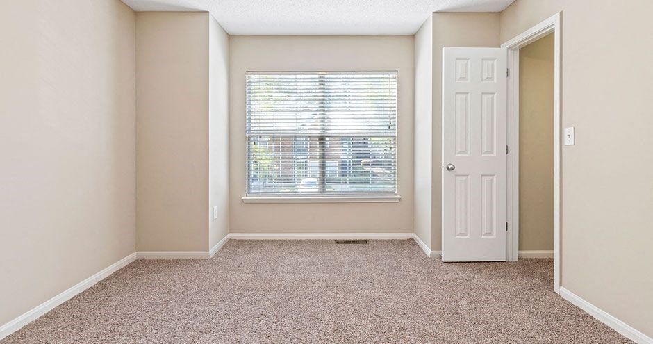 an empty room with a window and a white door