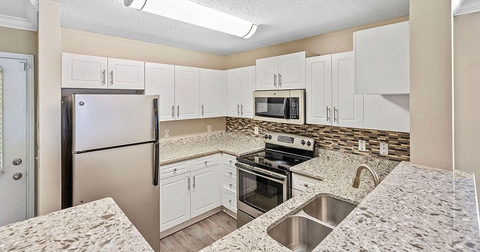 a kitchen with white cabinets and a stainless steel refrigerator