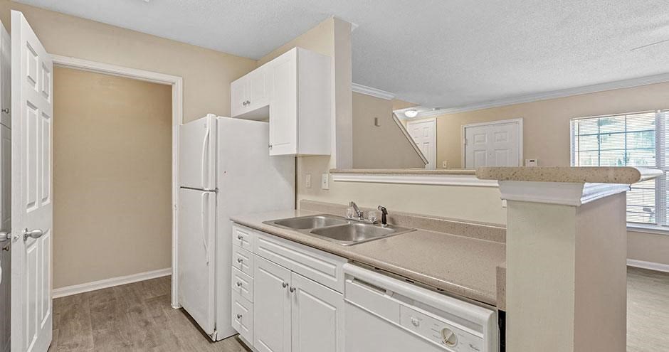 an empty kitchen with a sink and a refrigerator