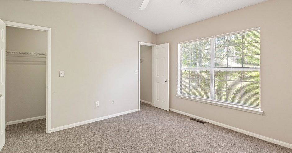 an empty bedroom with a large window and a closet