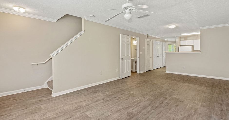 an empty living room with a ceiling fan