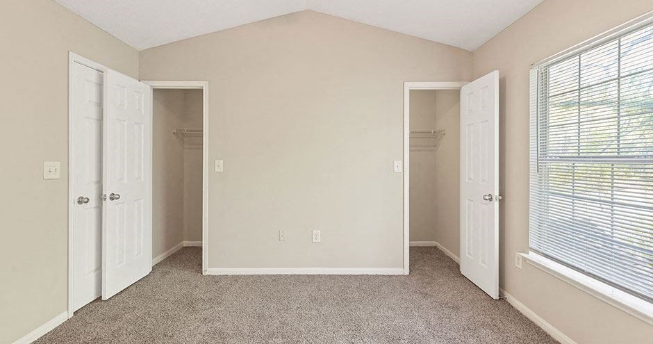an empty bedroom with a closet and a window