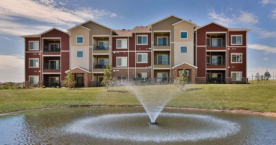 a fountain in a pond in front of an apartment building