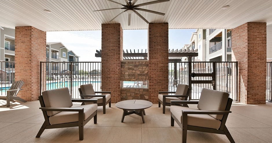 a patio with chairs and a table in front of a pool