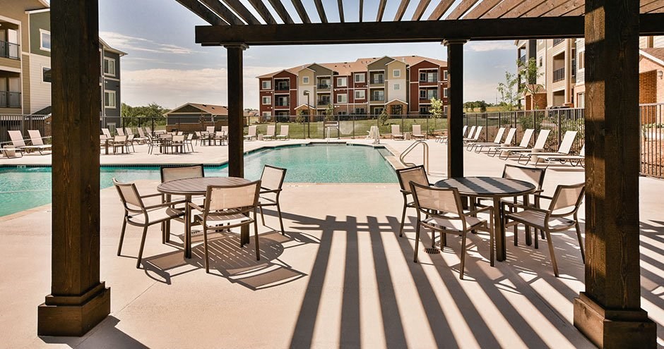 a pool with tables and chairs next to a building