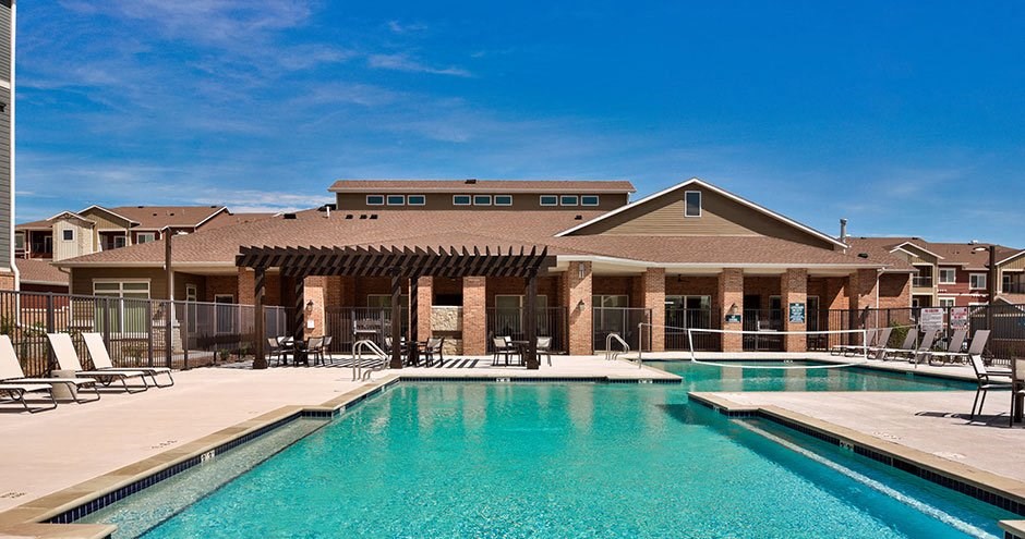 a large swimming pool with chairs in front of a building