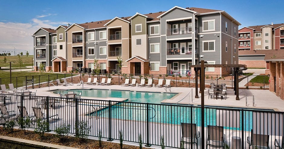 an apartment building with a pool and chairs
