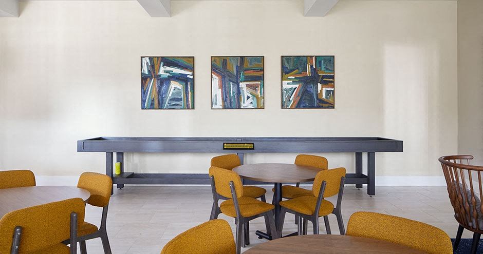 a room with a table and chairs and paintings on the wall