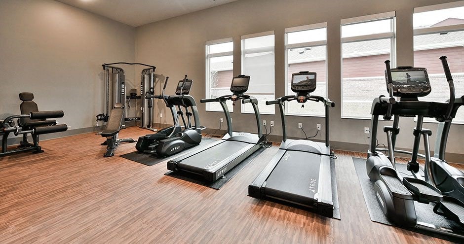 a gym with various exercise equipment on a wooden floor
