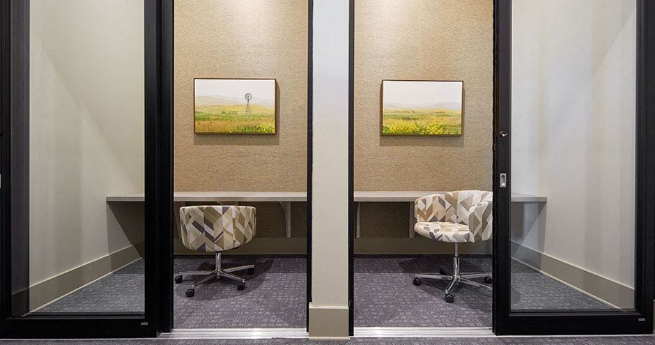 a conference room with two chairs and two pictures on the wall