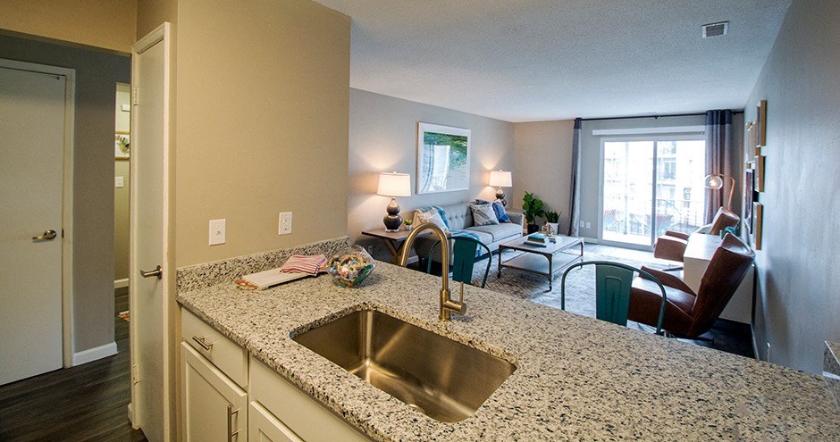 a kitchen with an island and a living room in the background