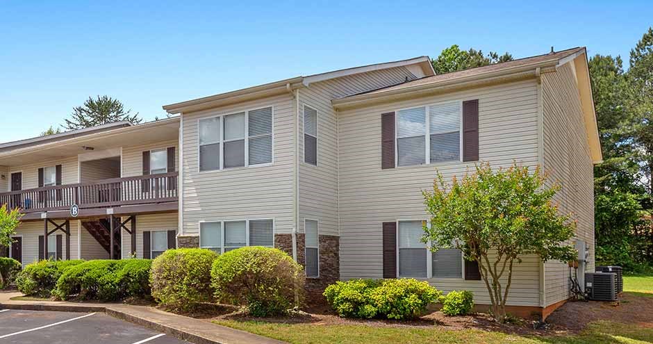 a white apartment building with a balcony and some bushes