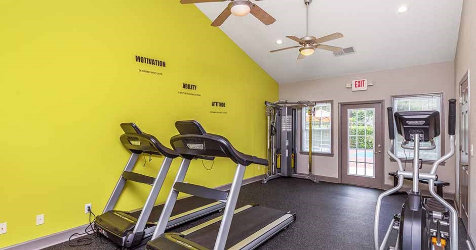 a gym with exercise equipment and a ceiling fan