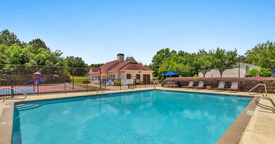 a large swimming pool with a house in the background