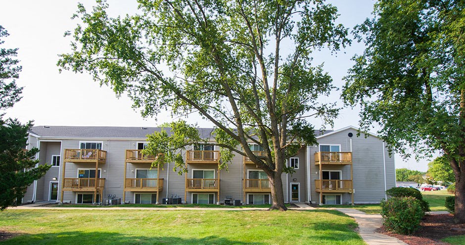 the outlook of an apartment building with grass and trees